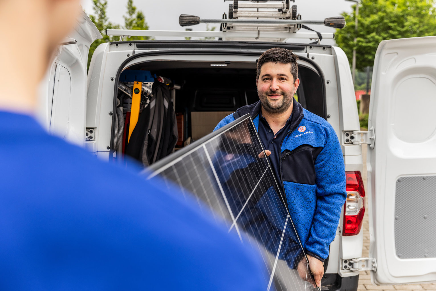 Zwei Mitarbeiter von Elektro Kessler laden ein Photovoltaik Element aus dem Auto aus